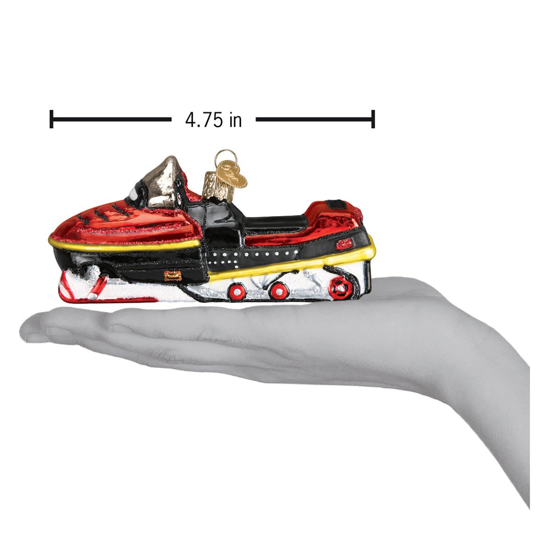 Snowmobile ornament on an open palm under a 4.75 inch length marker