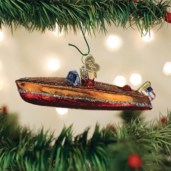 Wooden runabout boat ornament hanging on a lit Christmas tree with soft bokeh lights