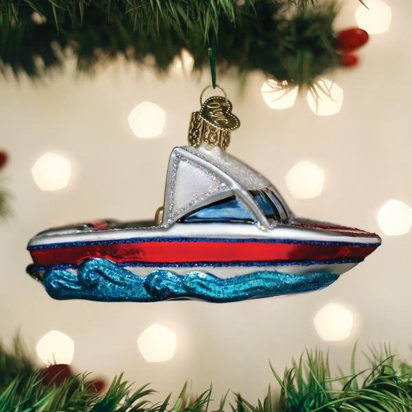 Red, white, and blue ski boat ornament hanging on a lit Christmas tree with warm bokeh lights