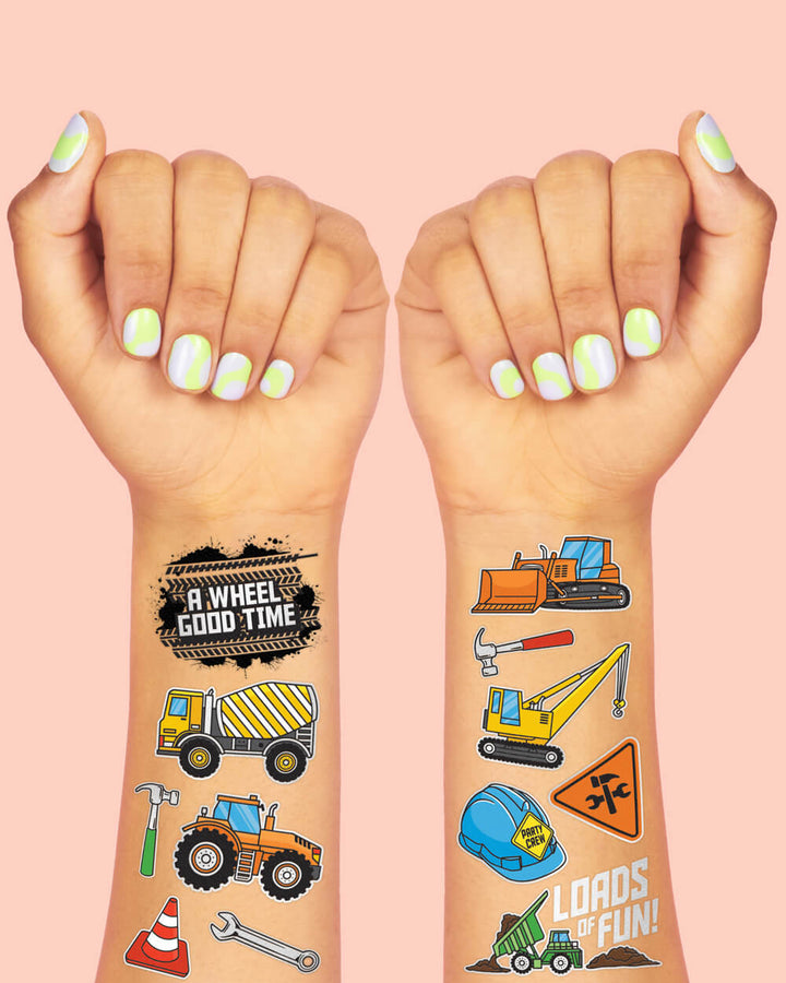 Construction temporary tattoos on two wrists showing a dump truck, digger, and road sign art