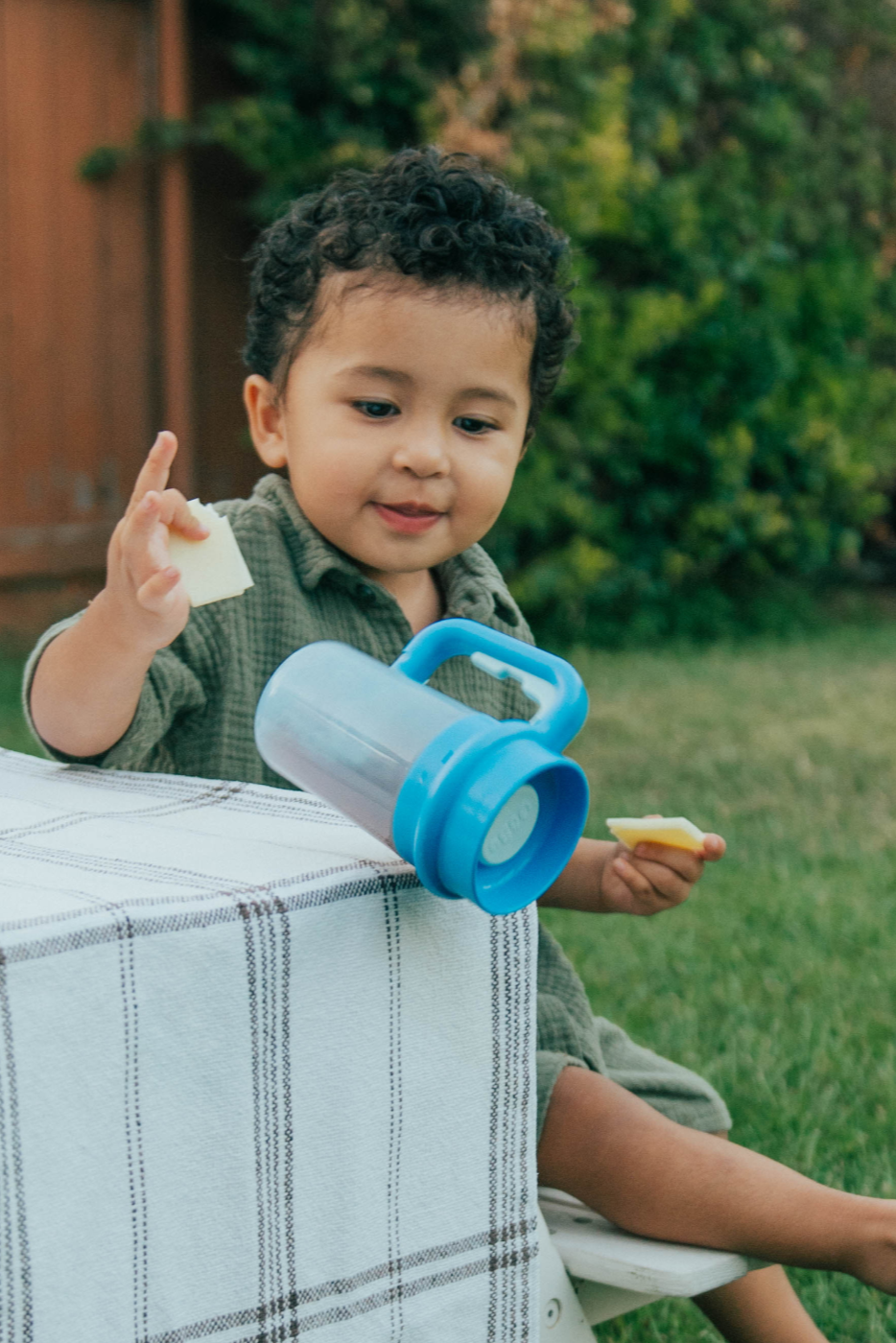 Toddler outdoors setting the blue Wonder Cup down on a bench