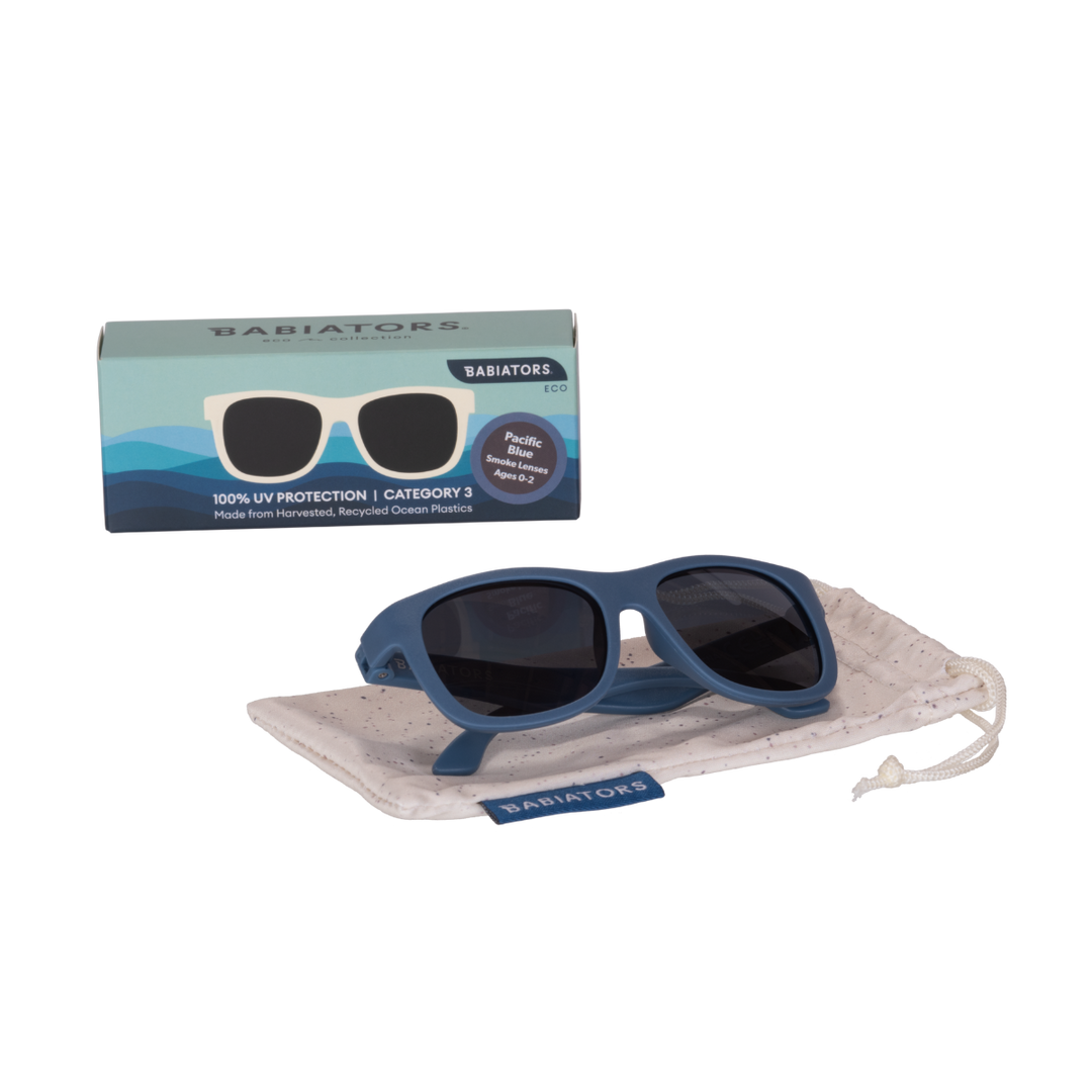 Blue eco aviator kids sunglasses folded on a speckled storage pouch beside the Babiators Eco box.