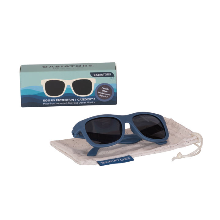 Blue eco aviator kids sunglasses folded on a speckled storage pouch beside the Babiators Eco box.