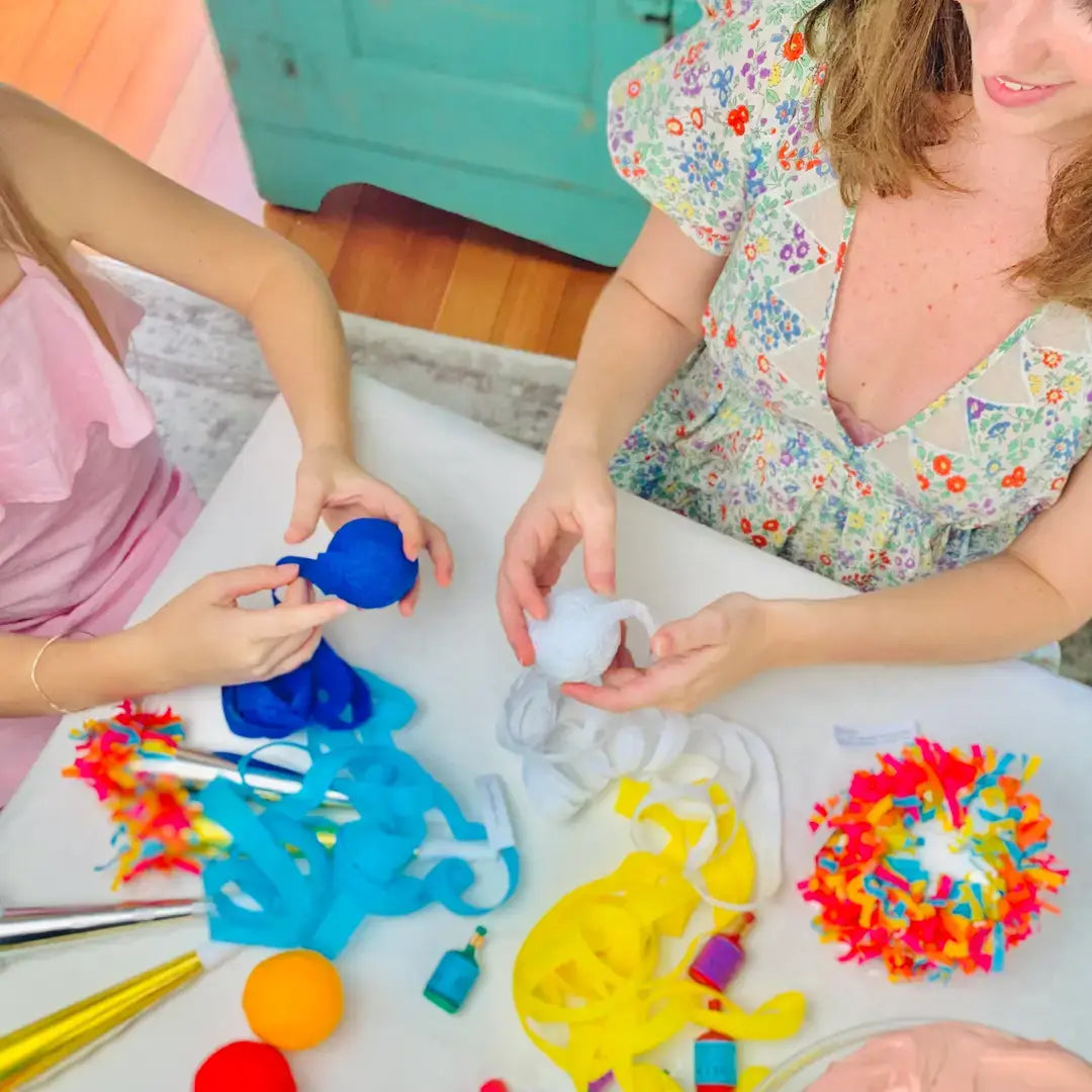 Mother and child unwinding blue and white surprise balls at a holiday party table