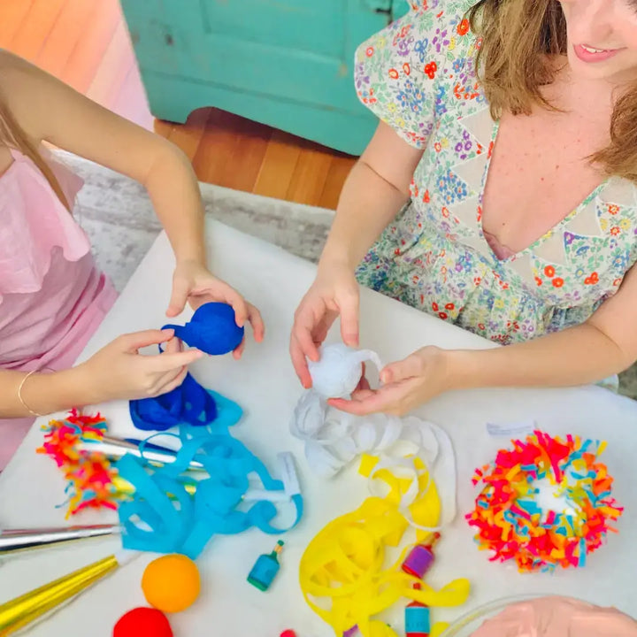 Mother and child unwinding blue and white surprise balls at a holiday party table