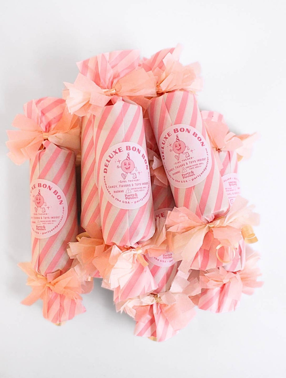 Pink striped deluxe surprise bon bons piled with peach tissue fringe for a girls' birthday party table