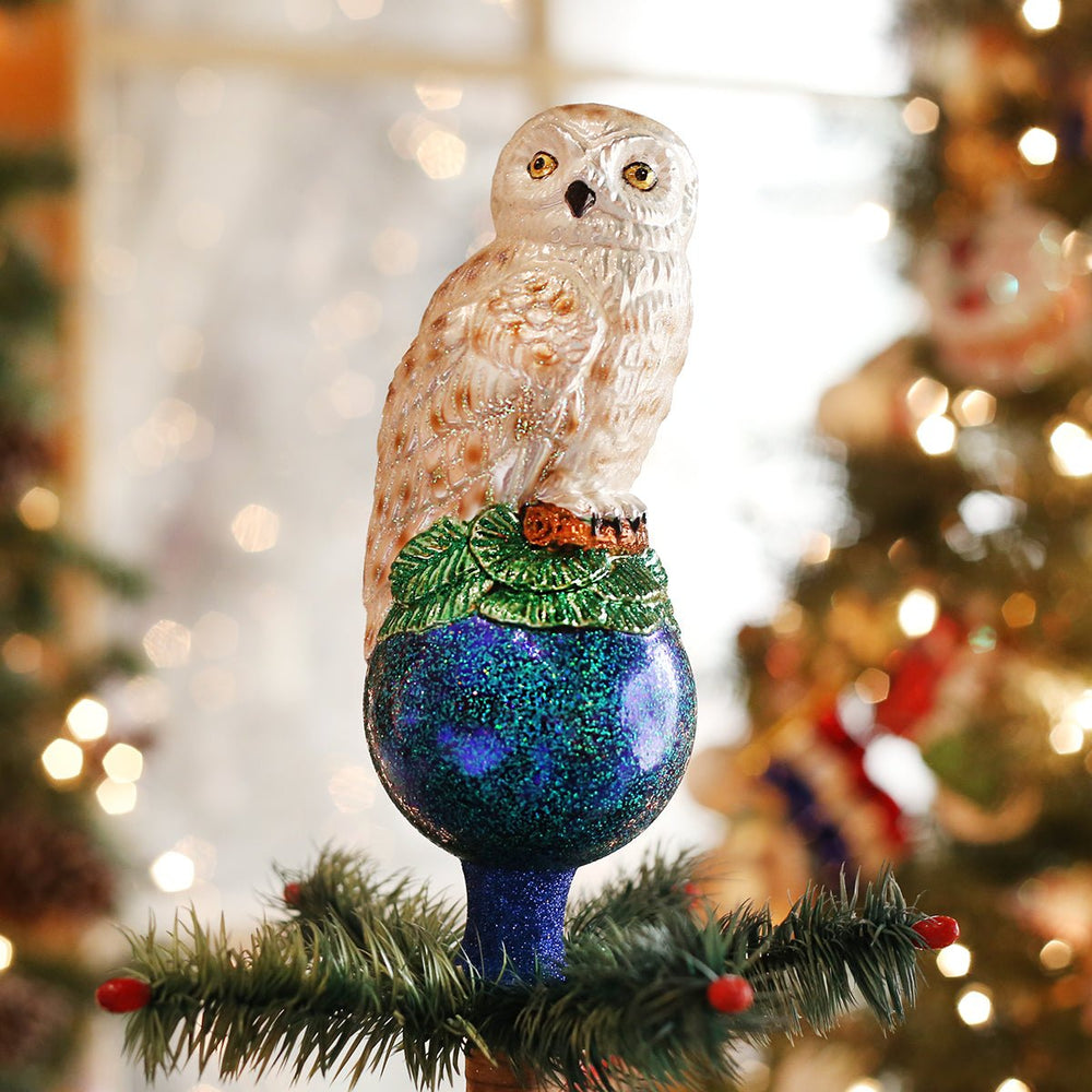 Snowy owl glass tree topper on top of a lit Christmas tree