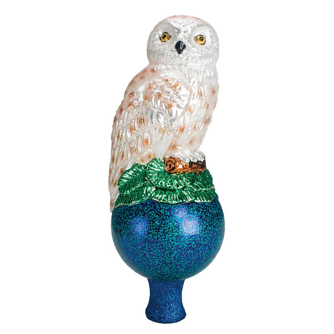 Snowy owl tree topper perched on greenery above a deep blue glitter ball, on white