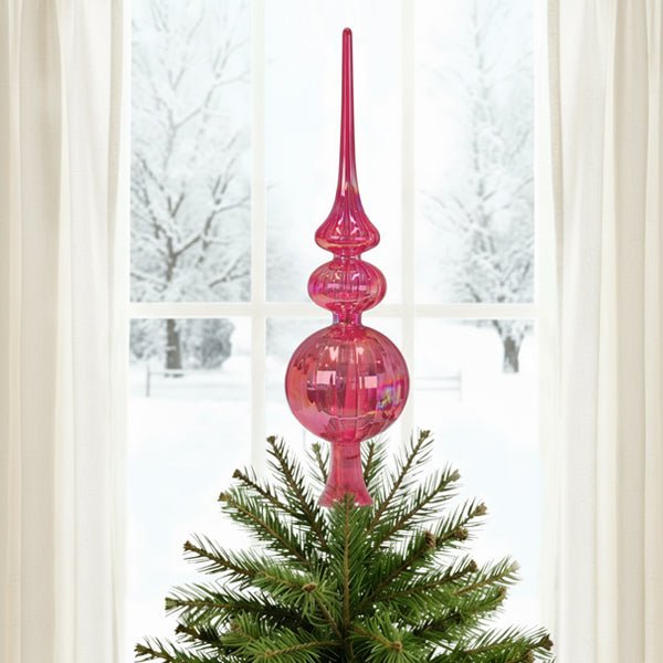 Pink glass finial tree topper on a Christmas tree in front of a snowy window