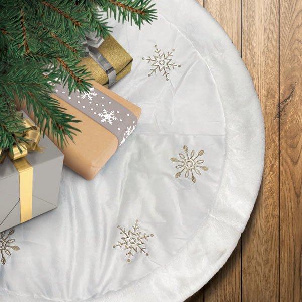 Ivory snowflake tree skirt under a Christmas tree with gold wrapped gifts
