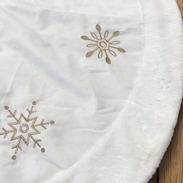 Close-up of gold snowflake embroidery on ivory fabric with the plush faux fur border