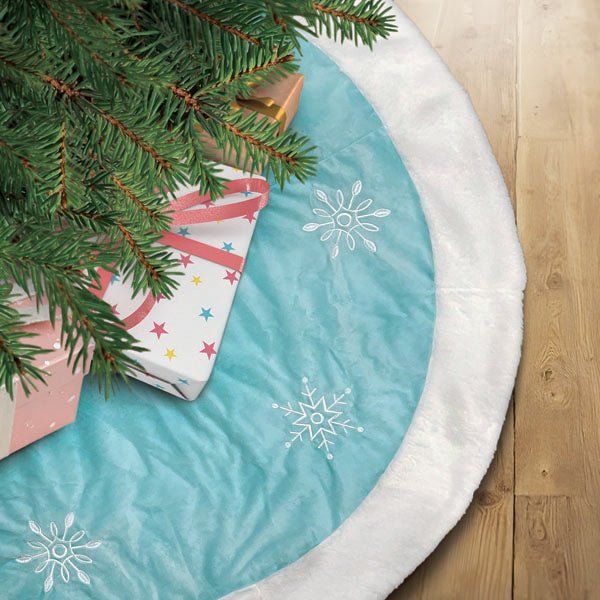 Pastel blue snowflake tree skirt under a Christmas tree with pink wrapped gifts