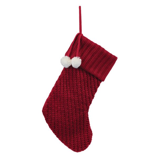 Front of the red knit Christmas stocking with a fold-over cuff and two white pom poms, on white