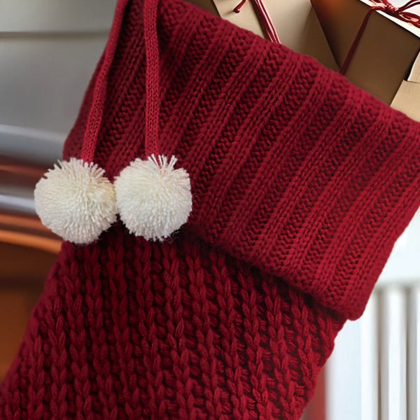 Close up of the red ribbed knit cuff and two fluffy white pom poms on the hanging loop