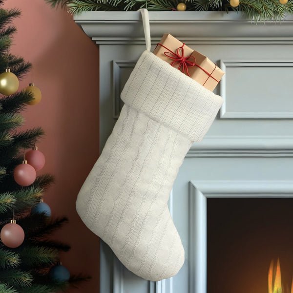 White cable knit stocking hanging from a light blue mantel with a wrapped gift tucked inside