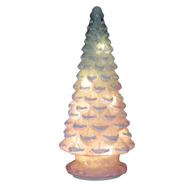 Pink glass tabletop Christmas tree glowing with its internal lights on, on white