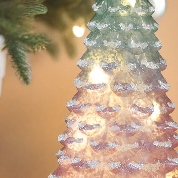 Close-up of the lit pink and mint glass tree with a real Christmas tree behind it