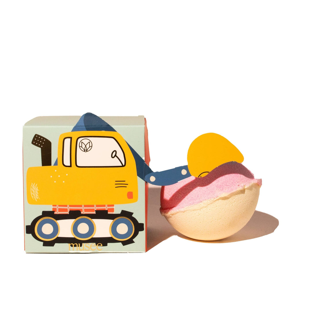 Pink and cream bath bomb with yellow digger scoop beside excavator box, a construction birthday party favor