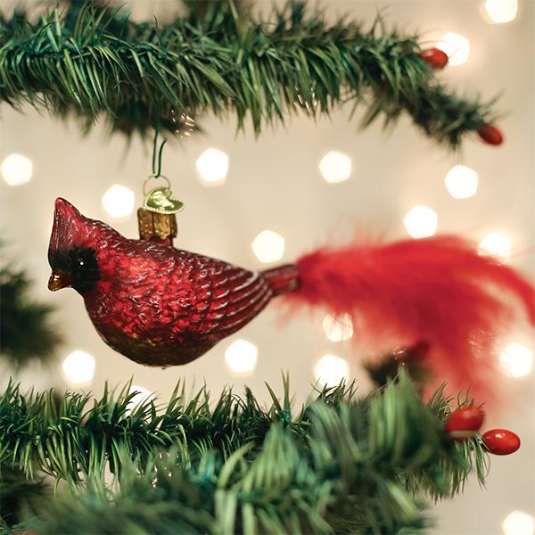 Vintage red cardinal ornament with a feathery tail hanging on a lit Christmas tree