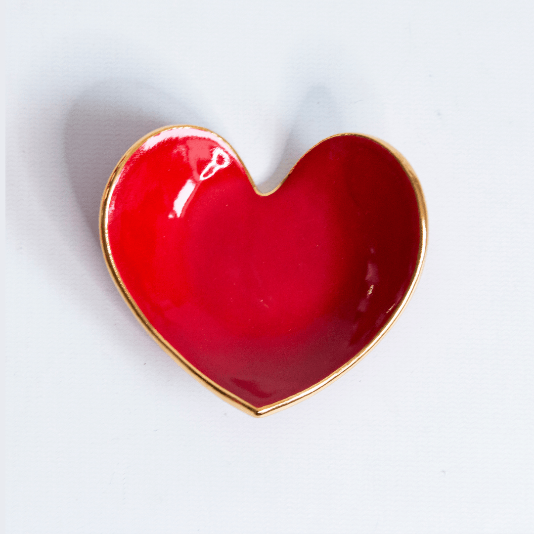 Close view of a glossy red heart ring dish with a gold rim