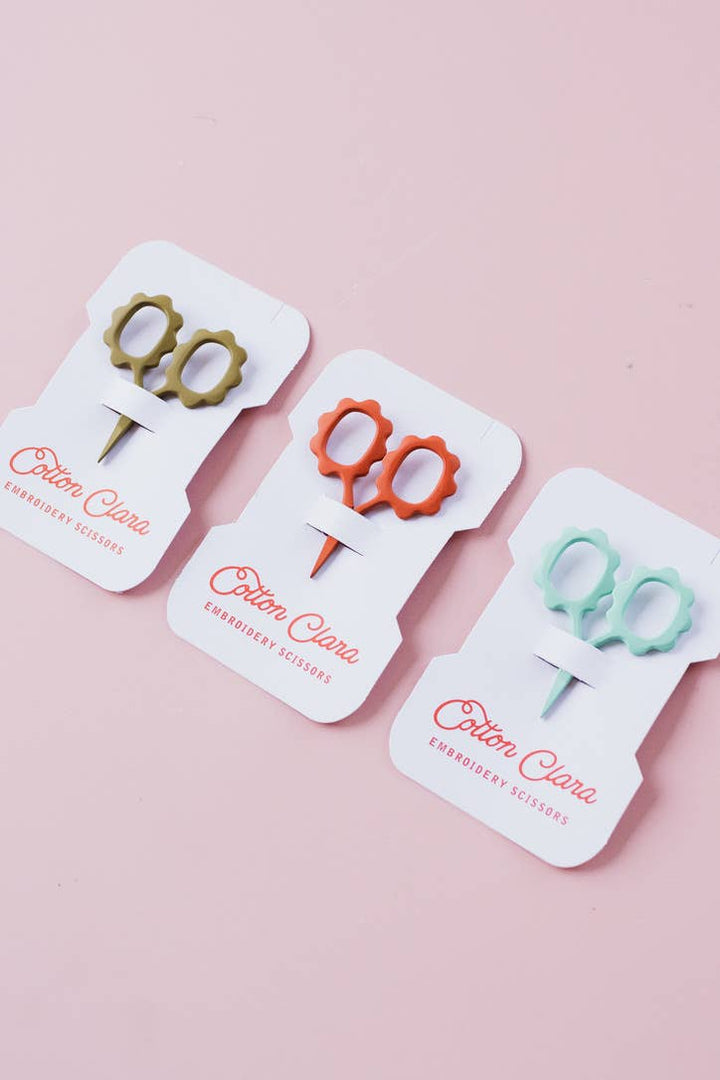 Olive, rust, and mint flower embroidery scissors cards on a pink background