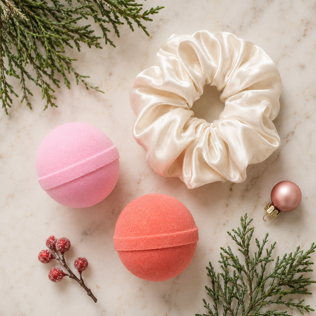 Flat lay of pink and coral mini bath bombs with an ivory satin scrunchie, berries and cedar for a holiday spa night
