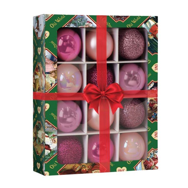 Angled view of the pink mini ball ornament set in a green gift box with a red ribbon