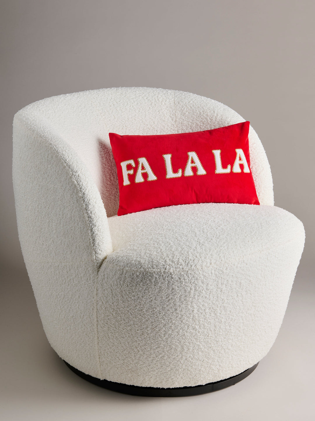 Red Fa La La Christmas pillow on a white boucle accent chair