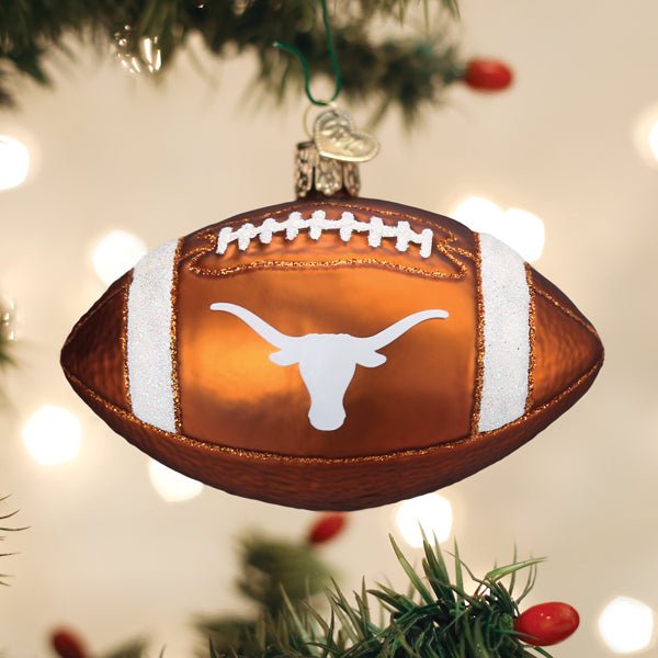 Brown Texas football ornament with a white longhorn logo hanging on a lit Christmas tree