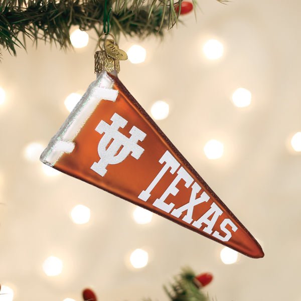 Burnt orange Texas pennant ornament hanging on a lit Christmas tree with soft golden bokeh