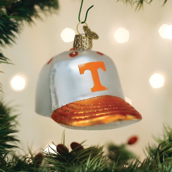 White and orange Tennessee Volunteers cap ornament hanging on a Christmas tree with warm bokeh lights
