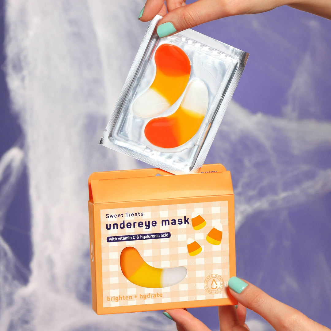 Hands lifting a foil sachet of candy corn patches above the open box, an easy Halloween boo basket surprise