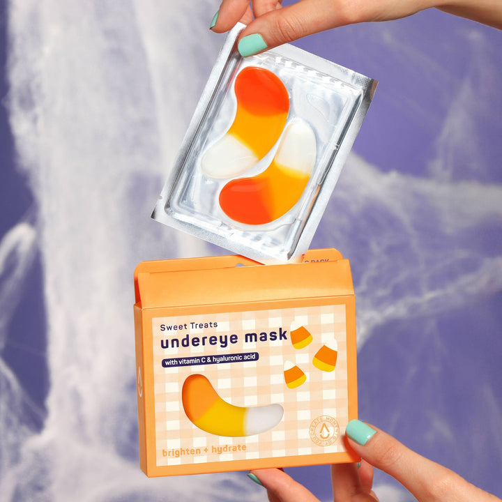 Hands lifting a foil sachet of candy corn patches above the open box, an easy Halloween boo basket surprise