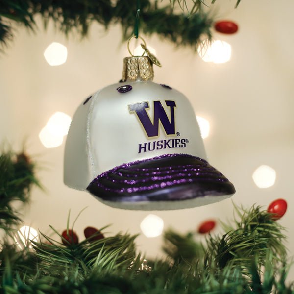 White and purple Washington Huskies cap ornament hanging on a lit Christmas tree