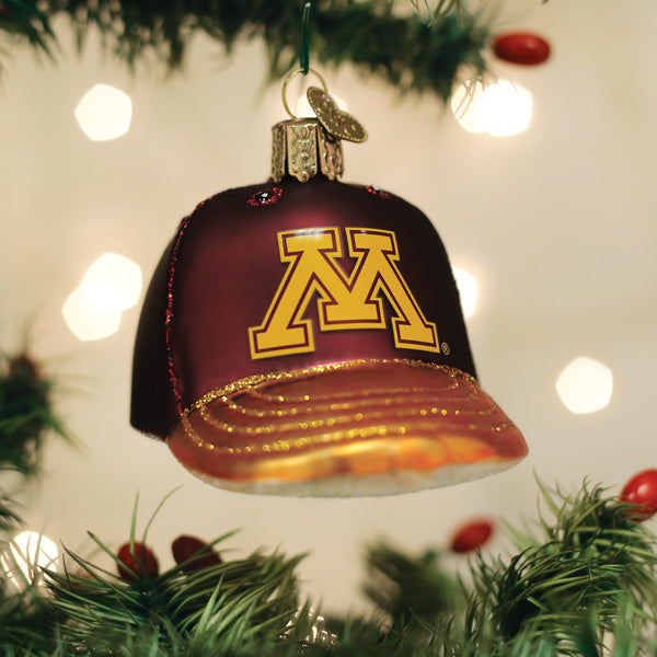 Maroon and gold Minnesota Golden Gophers cap ornament hanging on a Christmas tree with glowing bokeh lights