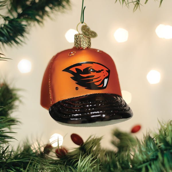 Orange Oregon State Beavers cap ornament hanging on a lit Christmas tree with glowing bokeh