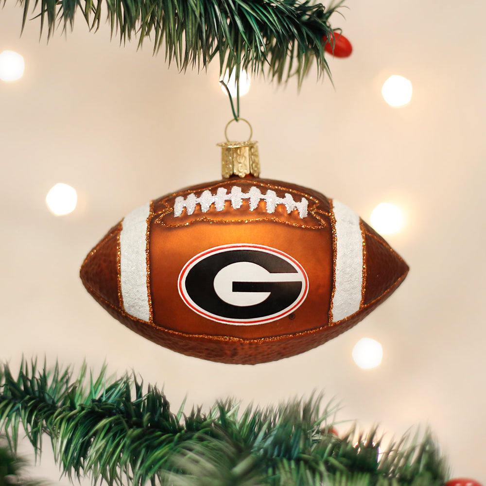 Georgia Bulldogs football ornament hanging from a green Christmas tree branch with soft lights behind