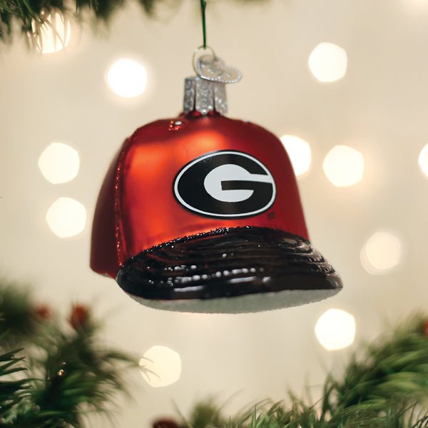 Red Georgia cap ornament hanging on a Christmas tree with warm bokeh lights behind