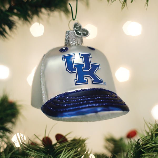White and blue Kentucky Wildcats cap ornament hanging on a Christmas tree with soft twinkle lights