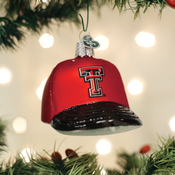 Red Texas Tech Red Raiders cap ornament hanging on a Christmas tree with glowing lights behind