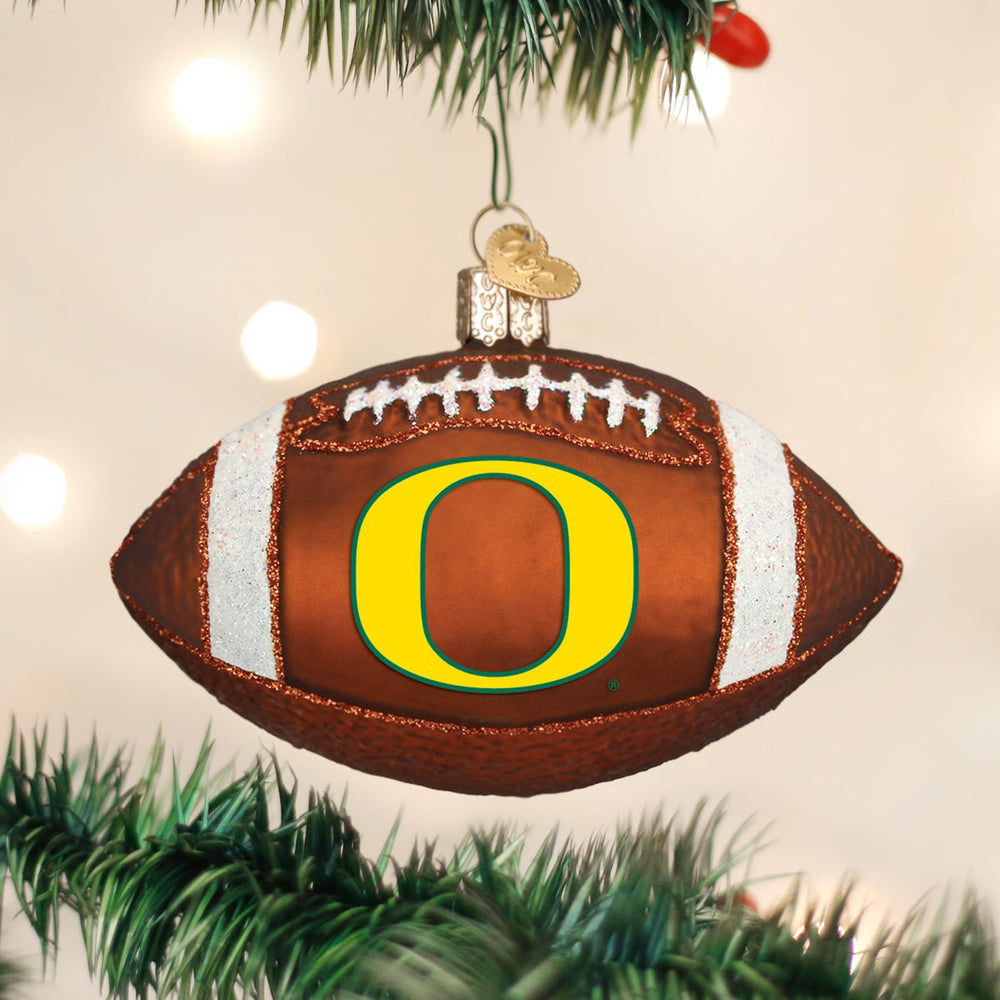 Oregon Ducks football ornament hanging on a Christmas tree with soft white lights behind