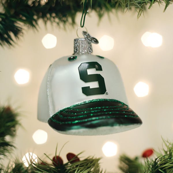 White and green Michigan State cap ornament hanging on a Christmas tree with glowing lights
