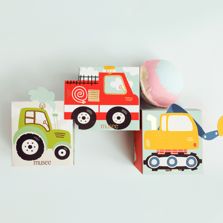 Musee tractor, fire truck, and excavator boxes stacked with a pastel bath bomb for a construction birthday party