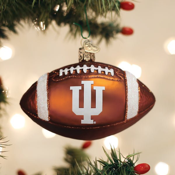 Brown IU football ornament hanging on a Christmas tree with warm glowing lights behind