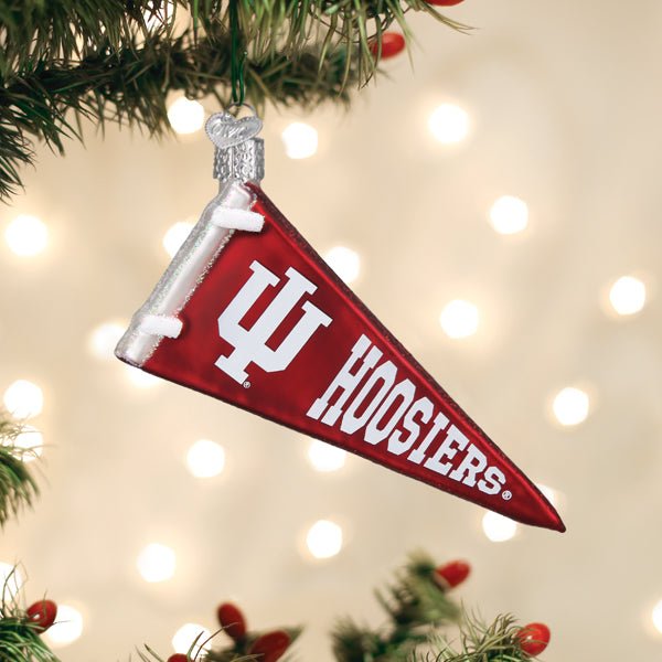 Crimson Indiana Hoosiers pennant ornament hanging on a Christmas tree with warm twinkle lights behind it