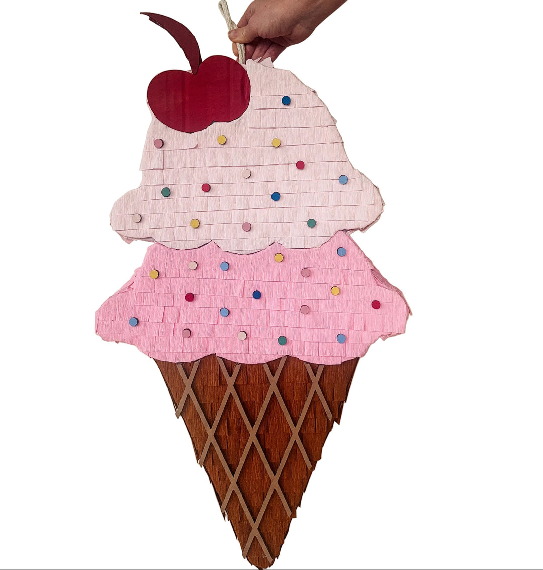 Ice cream cone-shaped piñata with a cherry on top against a beige background