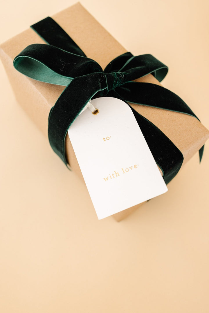 Back of an arch tag reading to and with love on a kraft box with a green velvet bow