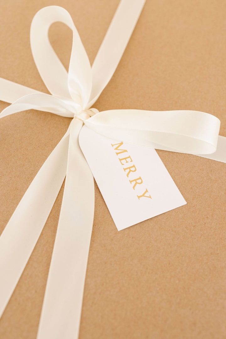 Arch letterpress tag tied with cream satin ribbon on a kraft paper present