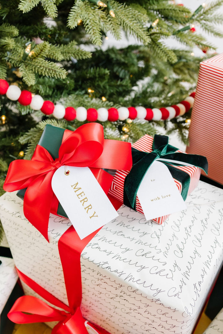 Christmas gifts by the tree with red satin and green velvet bows and arch Merry tags