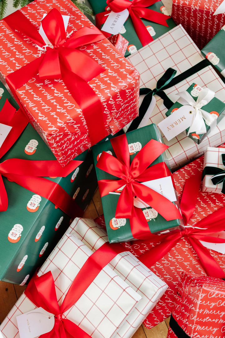 Close pile of traditional Christmas presents with red satin bows and arch gold foil tags